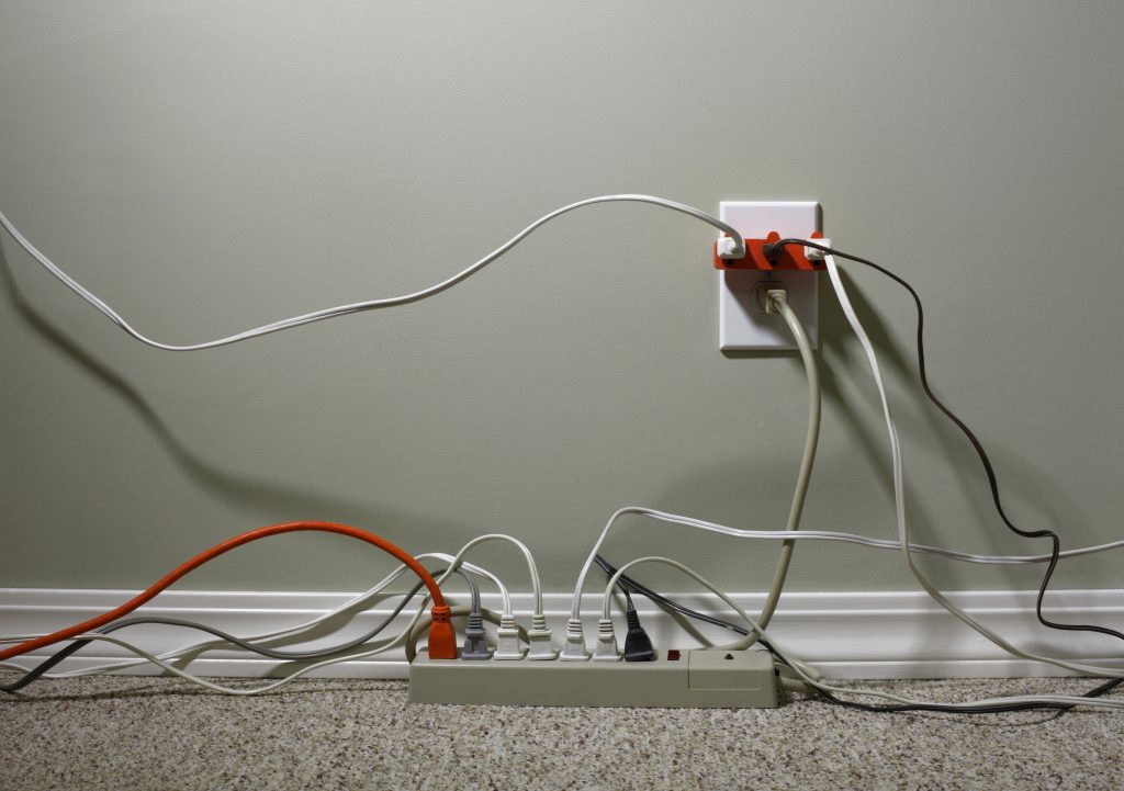 Still Life of an Electrical Wall Outlet Overloaded with Wires and Cables electrical wall outlet overloaded with plug and extensions cords